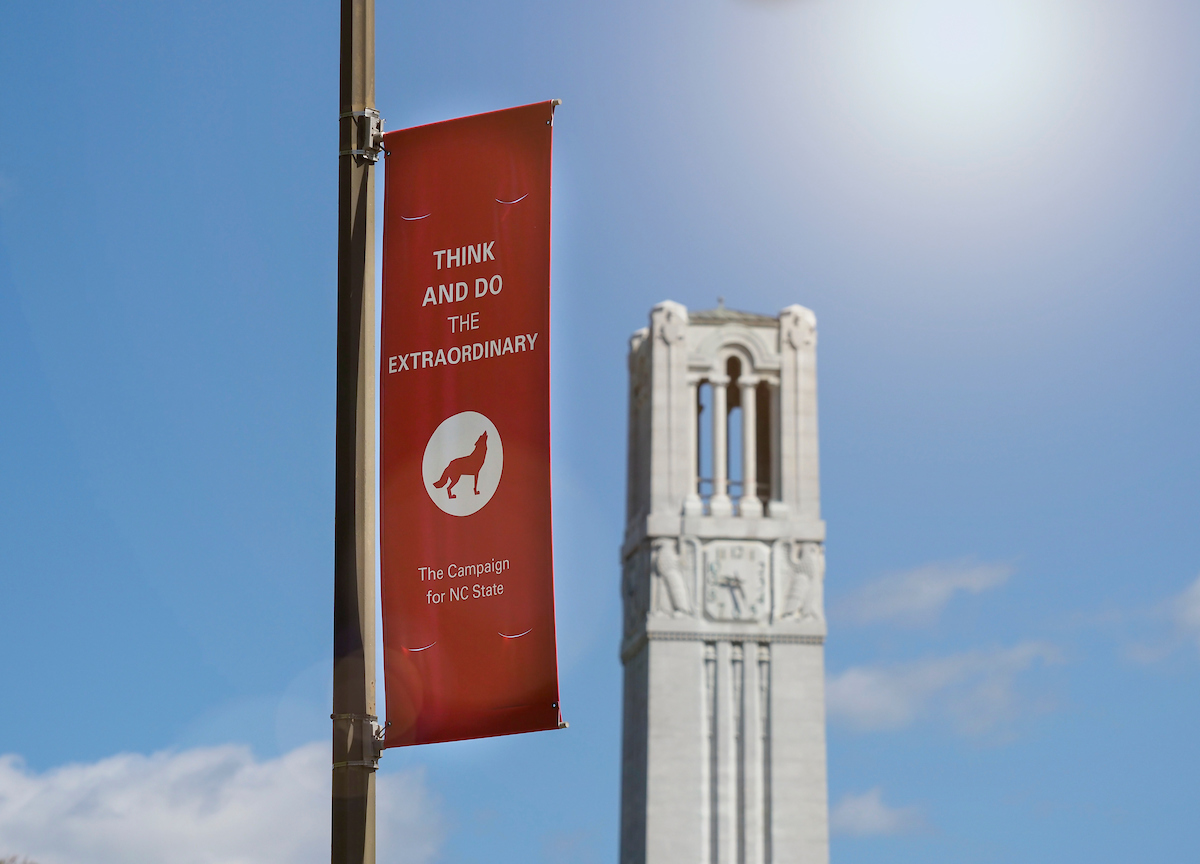 The NC State belltower with a Think and Do the extraordinary banner.